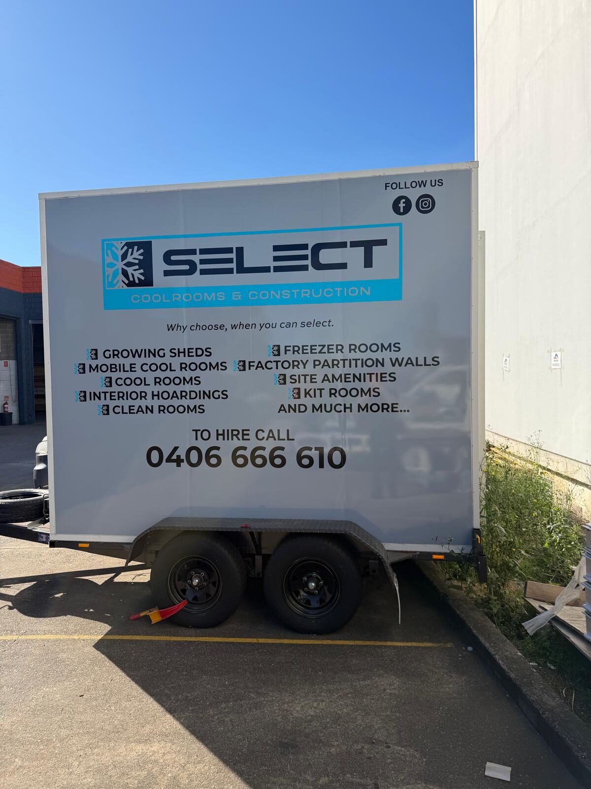 Side view of a Select Coolrooms and Construction trailer showing its tandem wheels and coupling.